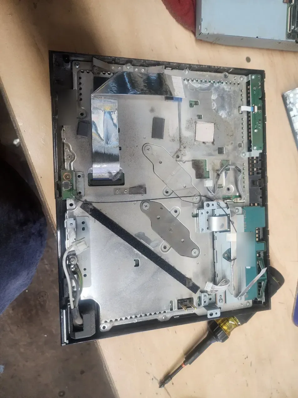 PS3 main metal shield exposed after the drive and power supply come out, with dust along the edges